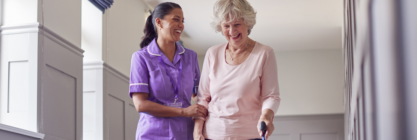 Assisted walking for elderly woman Carer helping elderly woman walk